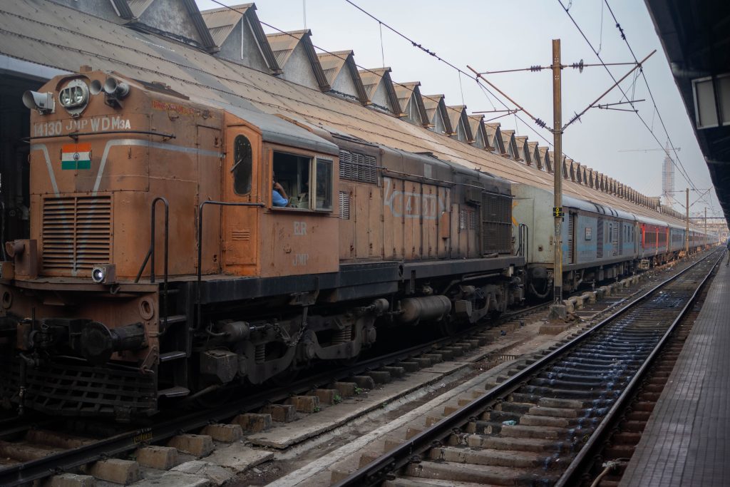 Bilde av tog som står på stasjon og tomme togspor ved siden