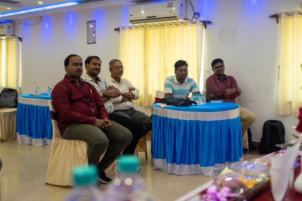 Fem stykker som sitter ved et bord og fører samtale med noen til høyre for kamera