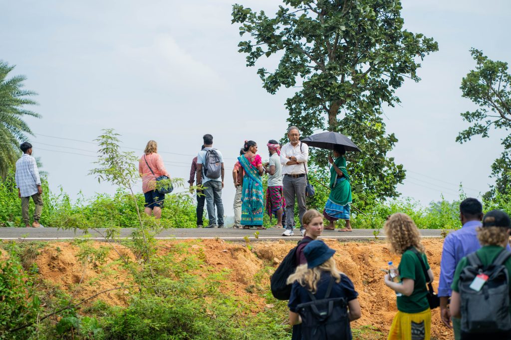 Personer som står på en vei lengre unna, like vel en åker