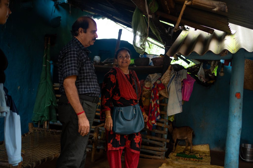 To personer som står under tak i en fattig bolig i India
