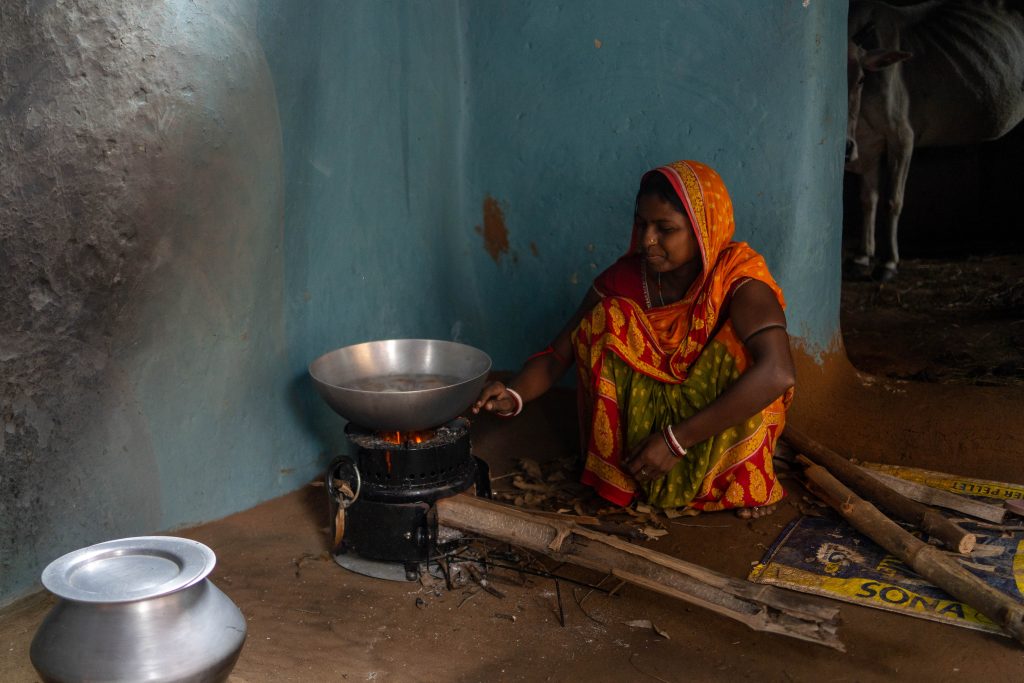 En kvinne ikledd oransje klær sitter ved en ovn