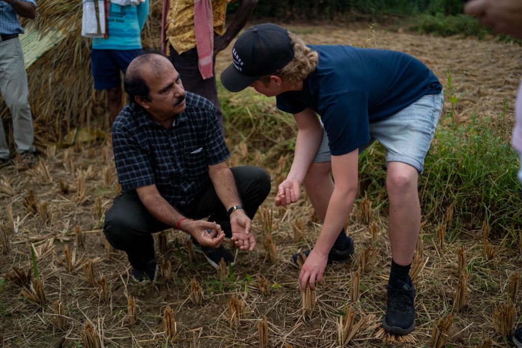To personer sitter på huk og bøyd ned som diskuterer jordbruk