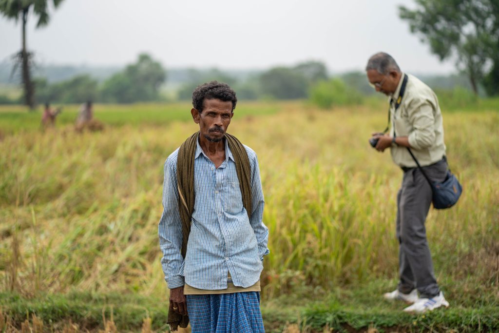 Eieren av en av åkerne står på åkeren sin og ser på besøkende