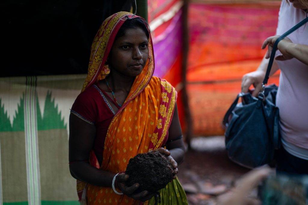 Ung kvinne som holder opp en jordklump med meitemark