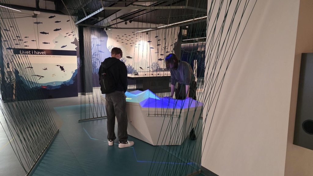 To elever som står ved en aktivitetsbod med blått lys