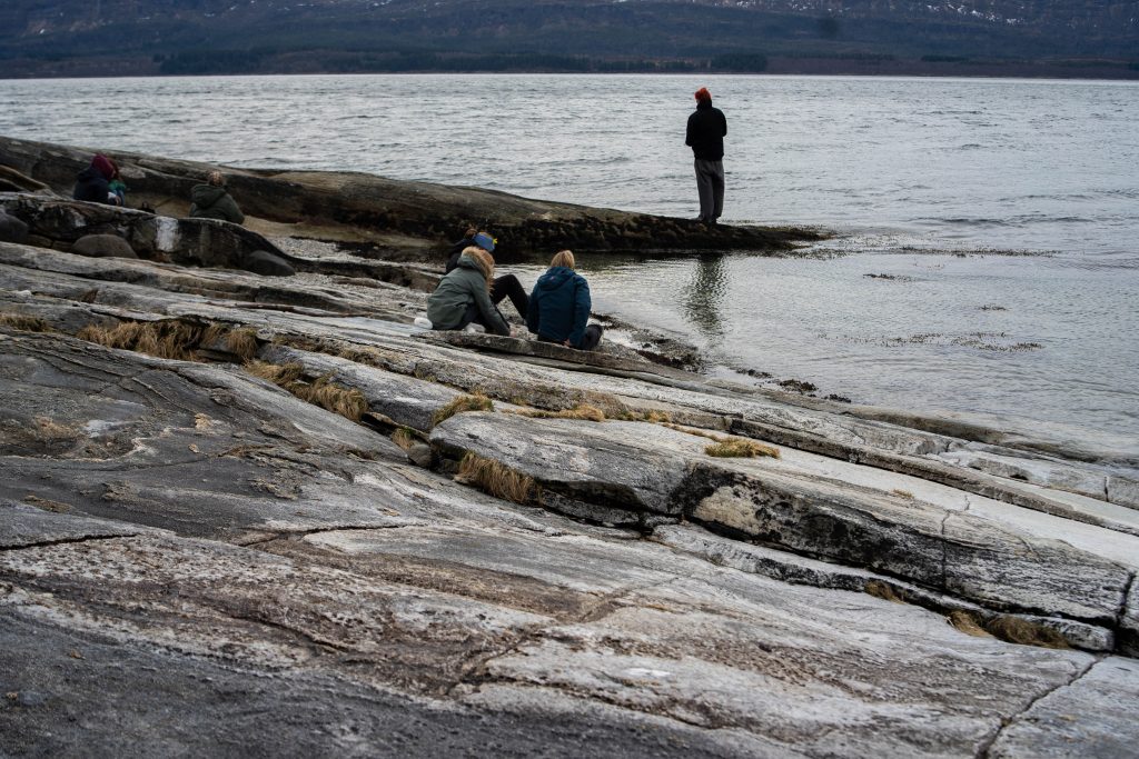 Berg i fjær hvor det sitter noen og lengre bort står noen å fisker