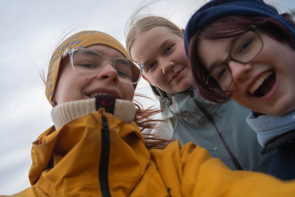 Tre elever som tar bilde av seg selv samlet tett med smil om munnen
