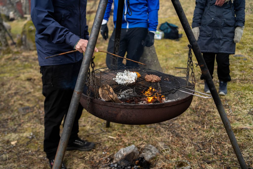Bålbanne med fyr i, og rist med mat