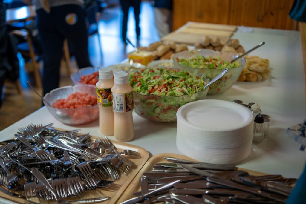 Et bord med salat, brød, dressing, bestikk, fat og skjærfjøler