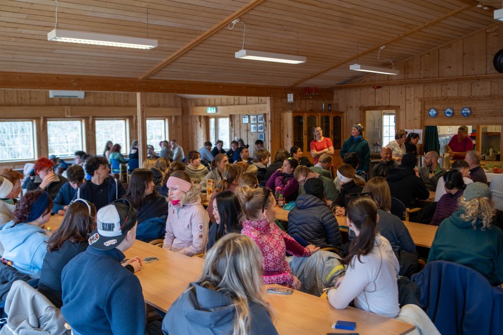 En hel skolegruppe samlet inne i et hus til lunsj