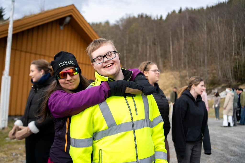 To elever som holder rundt hverandre og smiler bredt til kamera