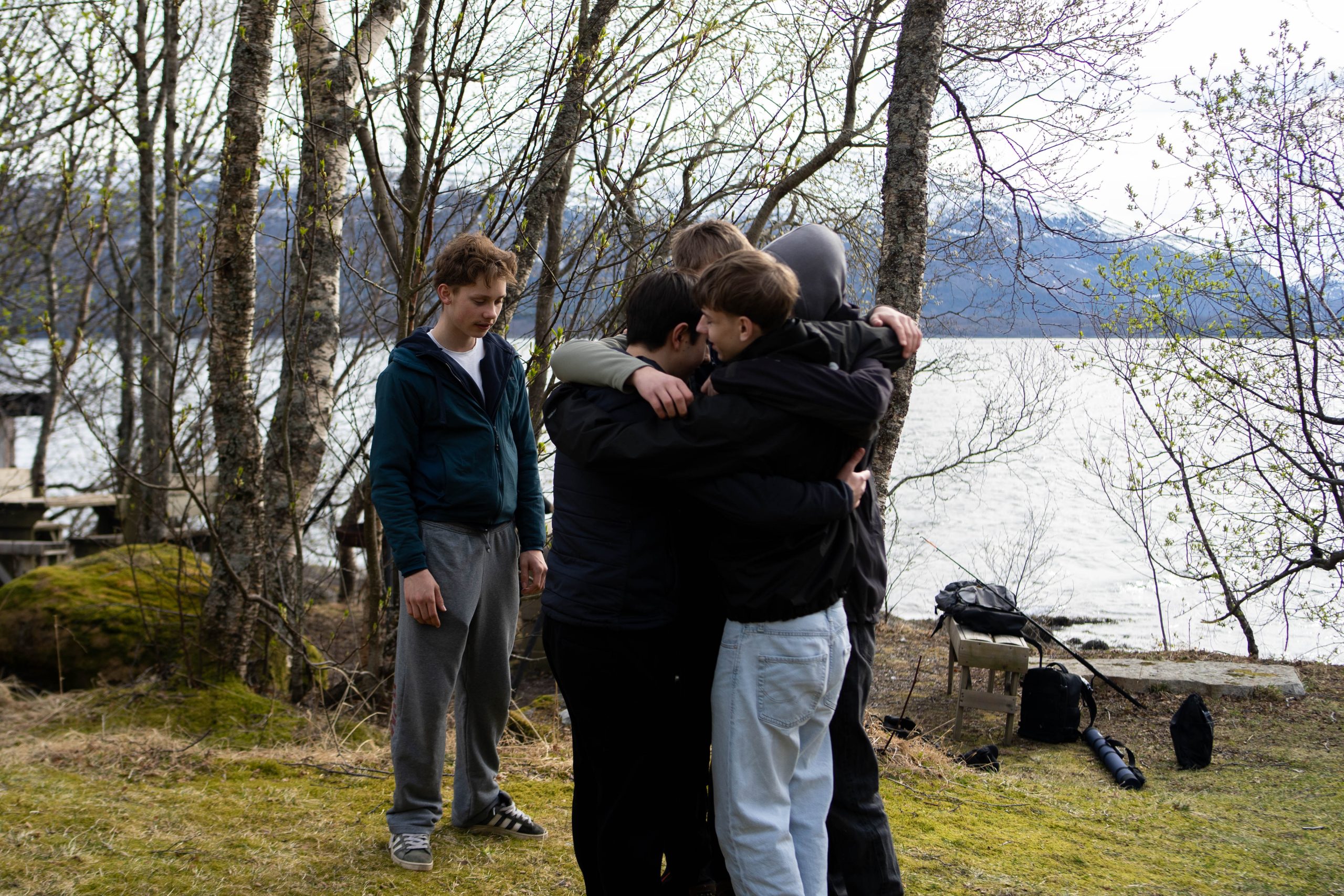 Fire gutter som står å holder om hverandre i en stor gruppeklem ute i