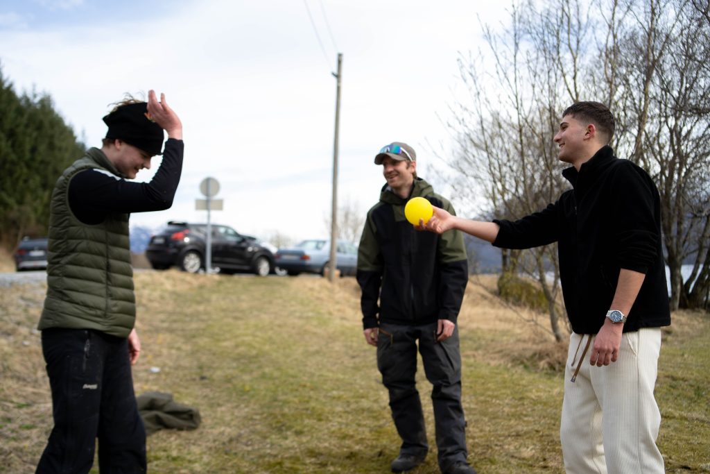 Tre stykker som spiller pickleball og den ene prøver å gi ballen til den andre