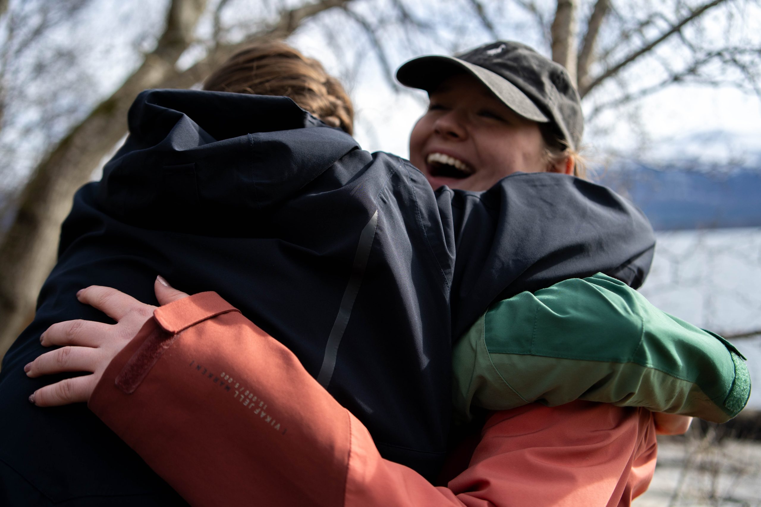 Tre elever tett oppi kamera som gir hverandre stor klem i latter